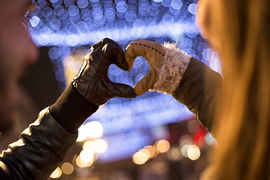 Winter background with couple making heart with gloved hands