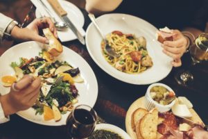 overhead view of Italian meal with pasta and salad with glasses of wine